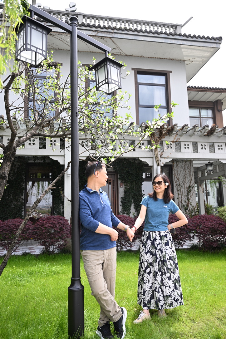 A couple holding hands in a blossoming garden before a traditional villa