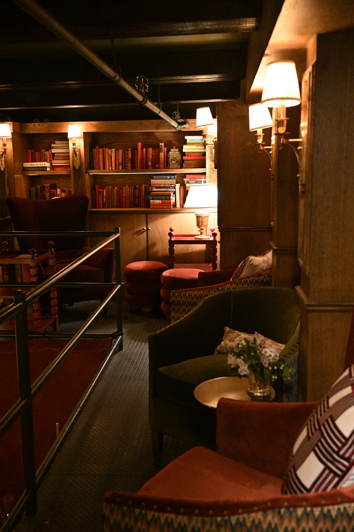 Cozy library lounge with a green velvet armchair and warm lamps
